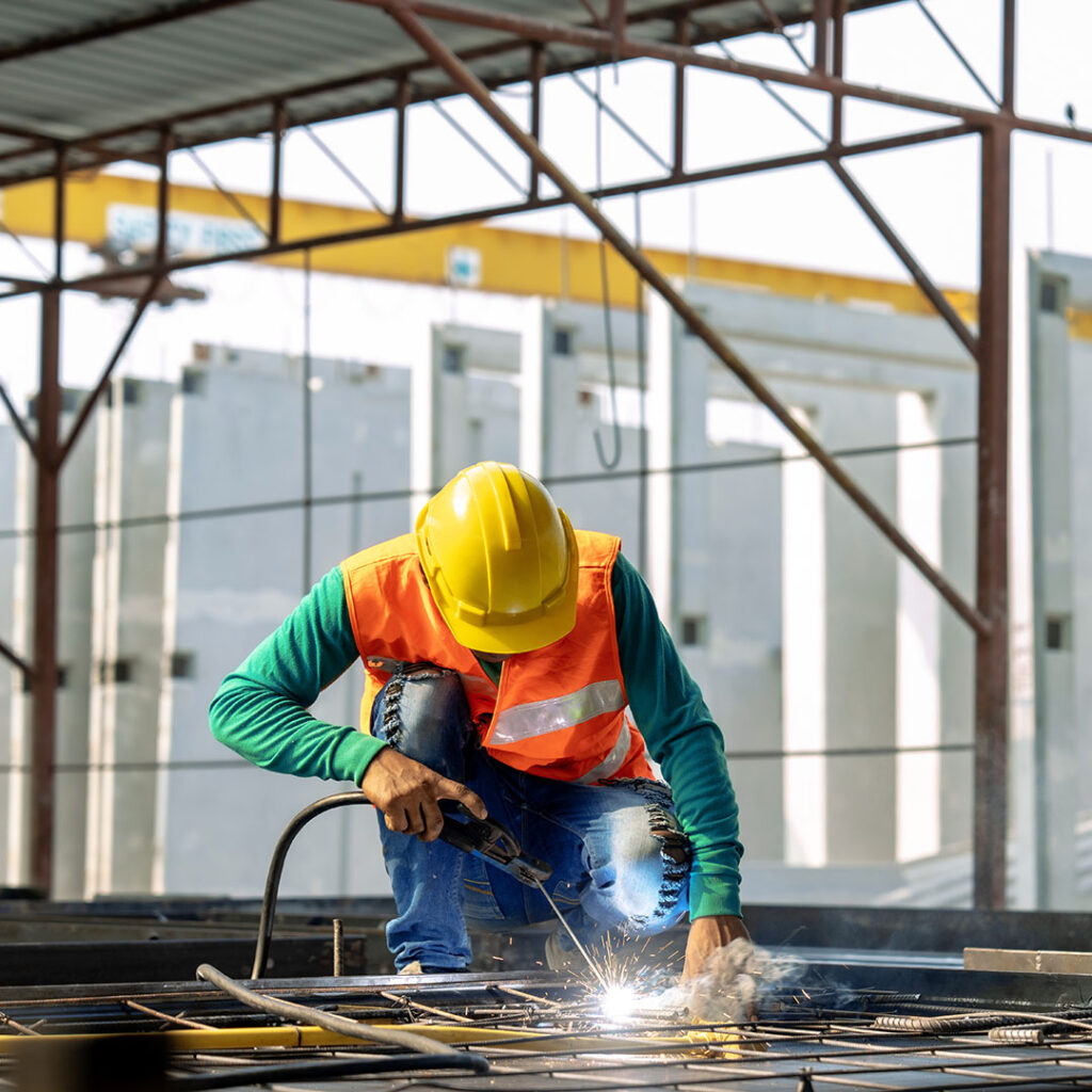 Man welding steel with a yellow hard hat on his head.