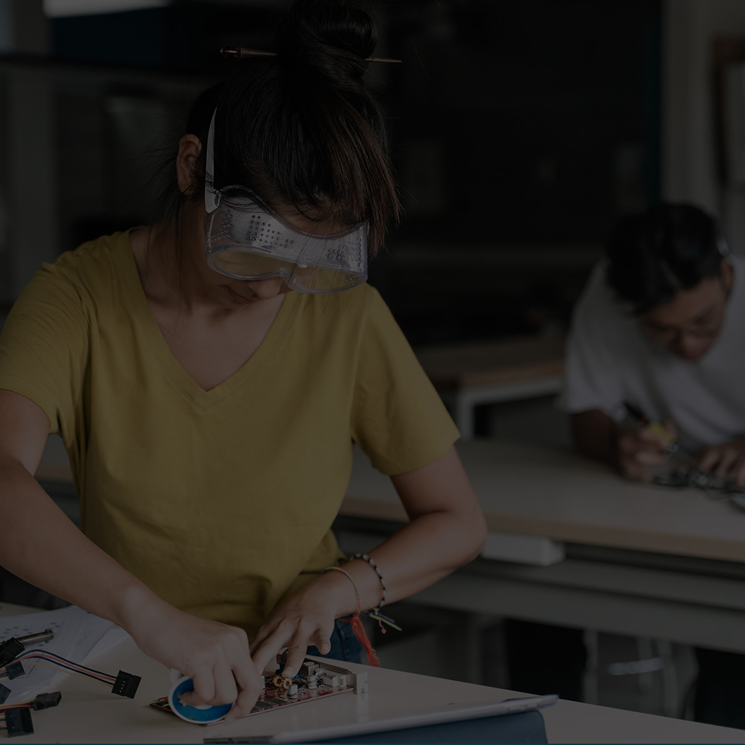 Female student in a lab working on a circuit board.